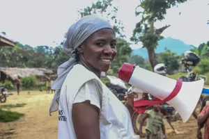 Promotora de salud de MSF con ayuda de un megáfono sensibiliza a los padres sobre la importancia y el bienestar de las vacunas para los niños y niñas. República Democrática del Congo.