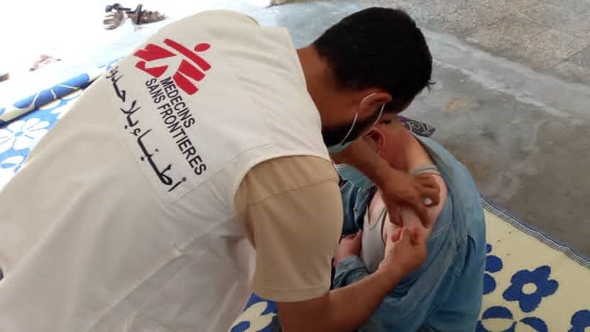 Un integrante de Médicos Sin Fronteras vacunando a una persona contra la COVID-19 en Siria