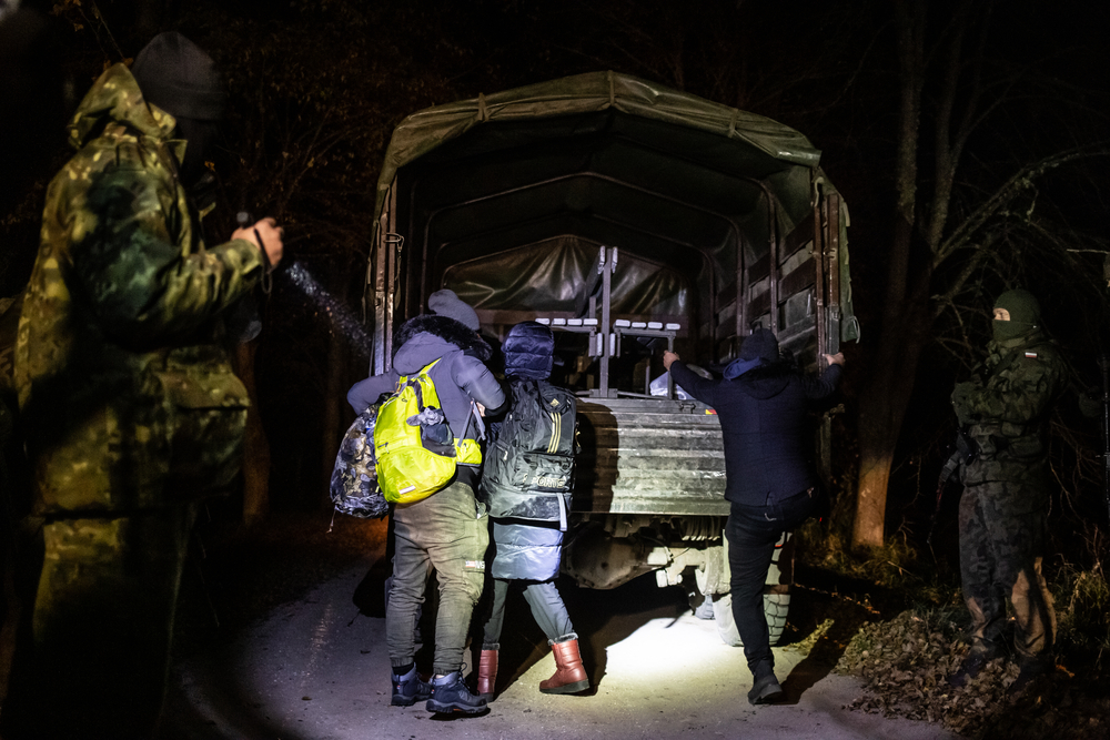 Guardias fronterizos polacos observan a una familia iraquí subiendo al camión militar. 