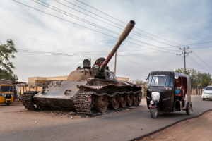 Un taxi rickshaw rodea un tanque destruido de las Fuerzas Armadas sudanesas.