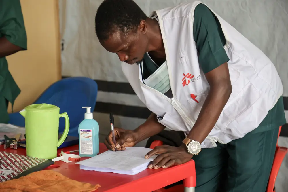 Muhammad Faysal Abdullahi, auxiliar de enfermería, toma algunas notas en el centro de alimentación terapéutica para pacientes hospitalizados. 