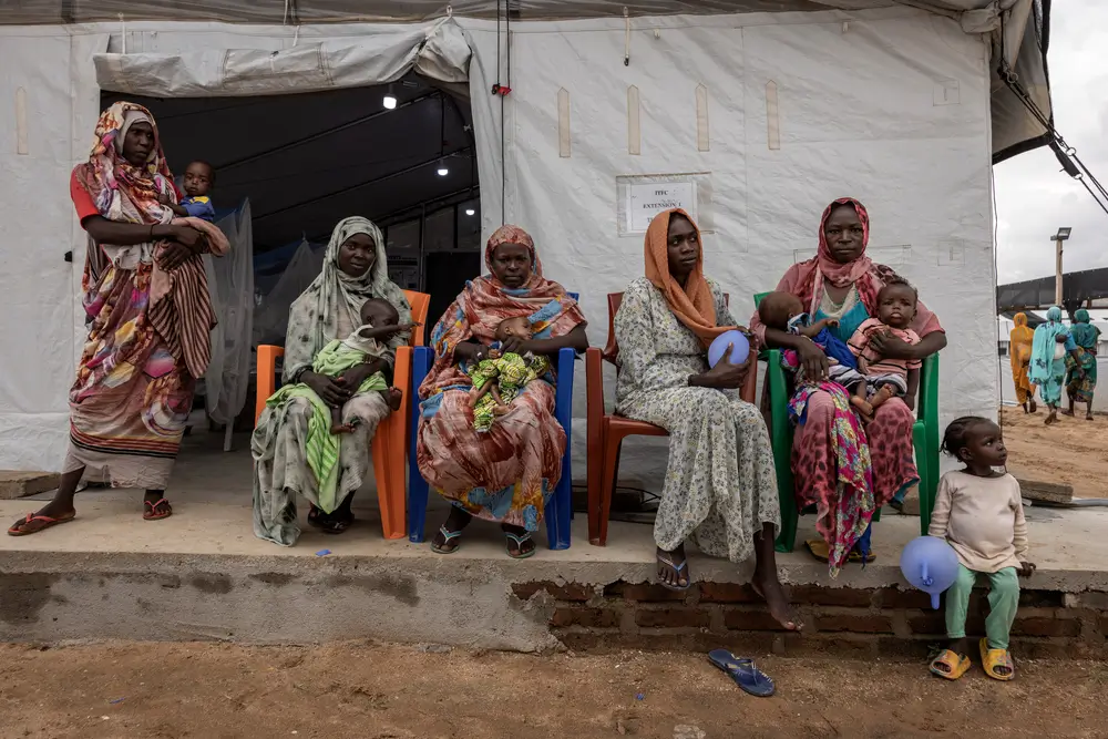 Mujeres refugiadas sudanesas sentadas fuera de una tienda de campaña de alimentación terapéutica de niños con desnutrición en el hospital de MSF en Metche, Chad.