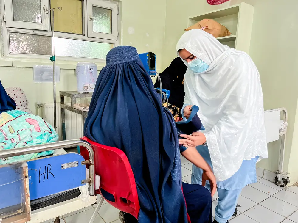 Una enfermera de MSF coloca un brazalete para medir la presión arterial en el brazo de una mujer para controlar su presión arterial. Sala de pacientes hospitalizados del Hospital de Maternidad de Khost. 