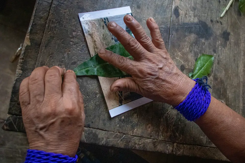 Rogelina Arce, en Puesto Indio, sanó simbólicamente con hierbas la fotografía de la calle principal de la comunidad, marcada por una incursión armada reciente. Puesto Indio, Alto Baudó, Chocó.