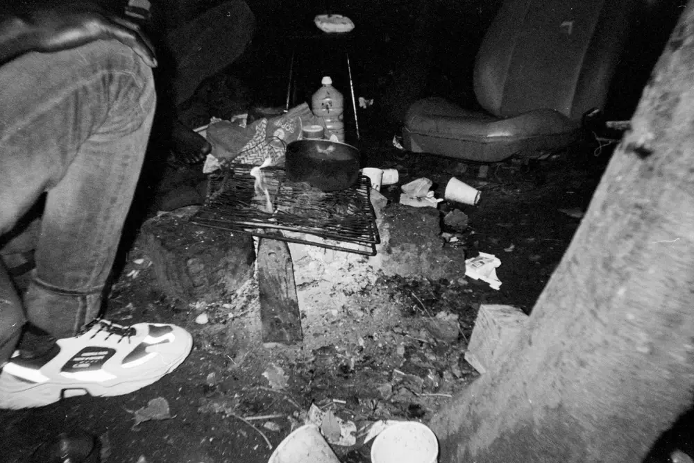 Exiliados encienden una hoguera para calentar comida en un campamento de Calais.
