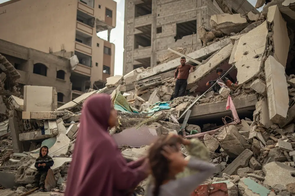 Trasel anuncio del alto al fuego en Gaza, una mujer y sus hijos intentan desenterrar sus pertenencias de debajo de los escombros en la calle Naser, en la ciudad de Gaza.