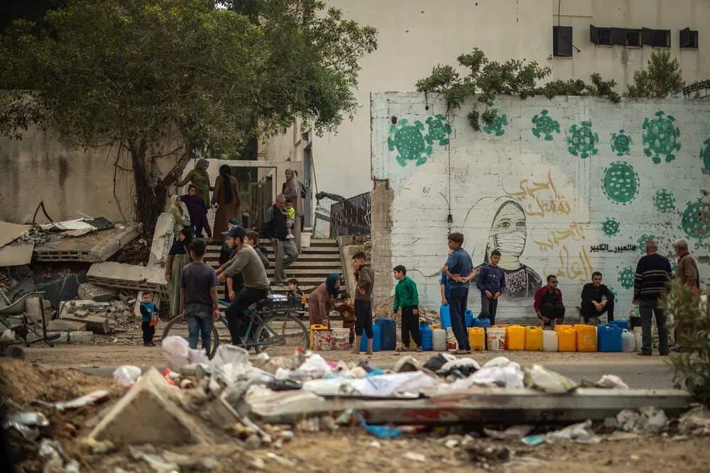 En la calle Al Jalaa de la ciudad de Gaza, la gente hace fila para recoger agua.