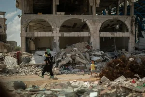 una mujer lleva a su hijo de vuelta a casa entre los escombros. Gaza, Palestina.