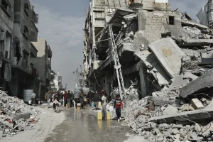 Personas recolectando agua junto a un edificio en riesgo de colapsar en Beit Lahia, en el norte de Gaza.