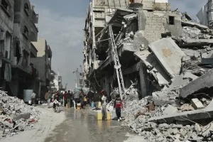La gente recoge agua junto a un edificio que está en peligro de derrumbarse en Beit Lahia, en el norte de Gaza.