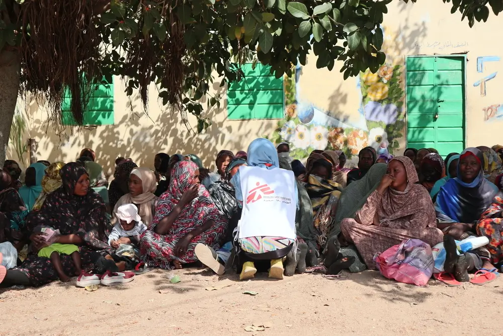 Personal de MSF habla con una de las madres admitidas en el programa de MSF para atender a mujeres lactantes y embarazadas que sufren desnutrición severa, mientras esperan recibir las canastas de alimentos.