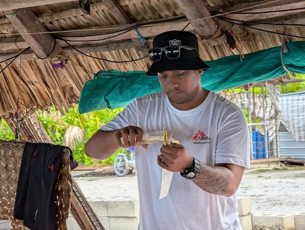 Mila Tirikai, supervisora ​​de agua y saneamiento de MSF, vierte una muestra de agua de pozo en una bolsa de clorofila para una prueba de coliformes fecales. Kiribati, enero de 2025.