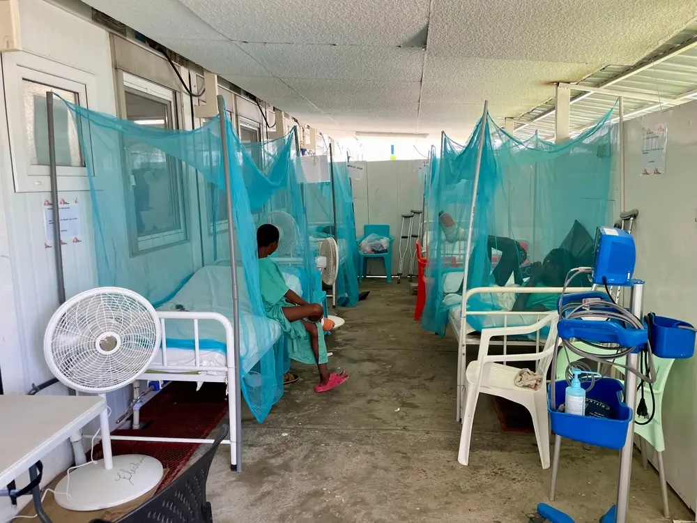 Un joven paciente está sentado en una cama en un pasillo de hospital improvisado enel hospital de MSF en Tabarre, Haití.