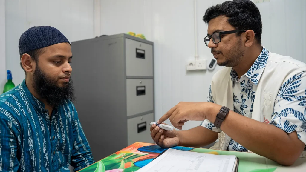 Un paciente con diabetes recibe atención médica. El médico de MSF le muestra una pluma de insulina.