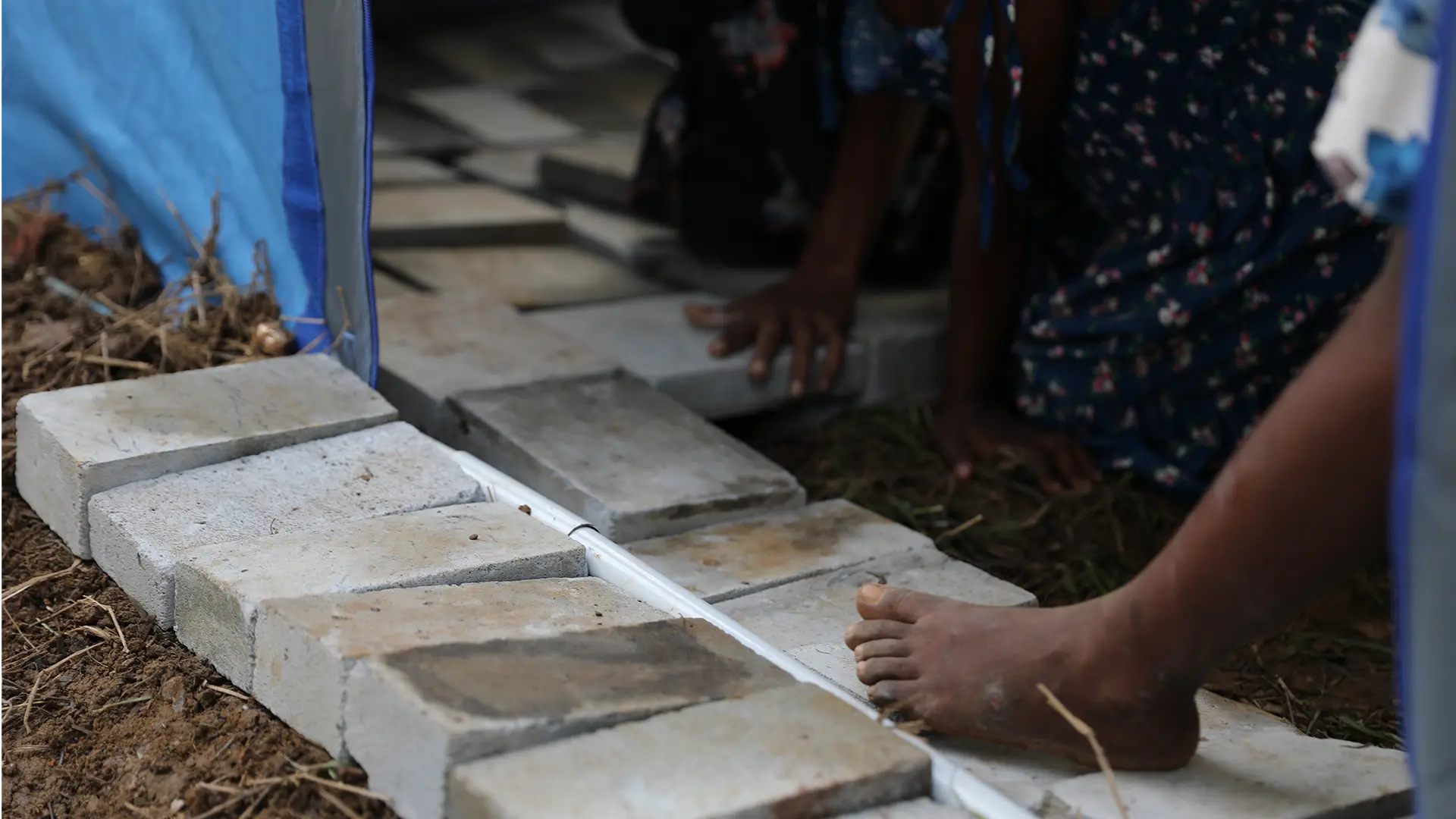 Las familias y los niños afectados están recolectando y colocando bloques de hormigón en el suelo para hacer sus refugios más habitables. Sri Lanka, 2025.