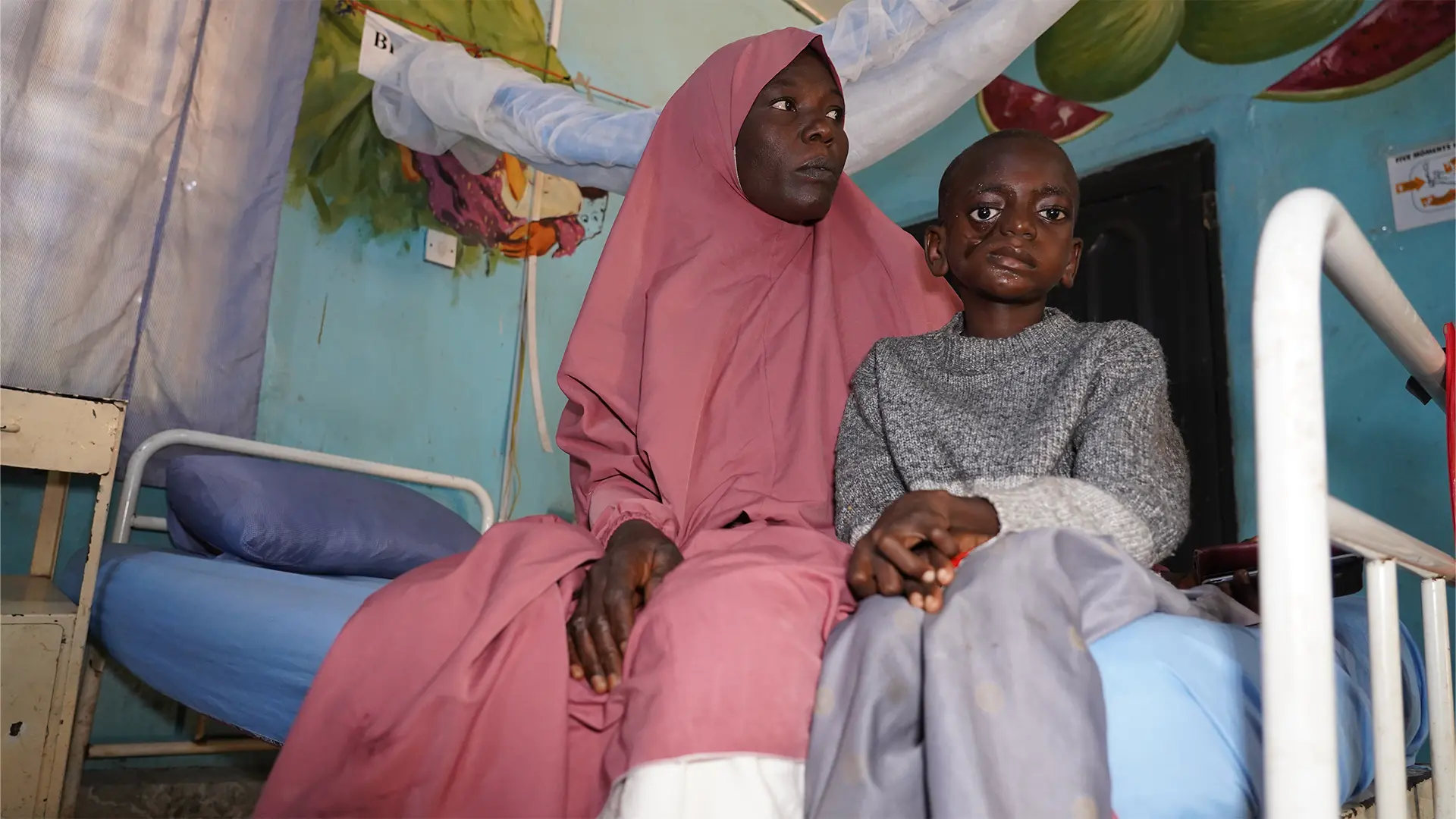 Shafa Saidu y su hijo, Umar Saidu, un paciente de noma, sentados dentro de una sala del Hospital Infantil Noma en Sokoto, Nigeria.