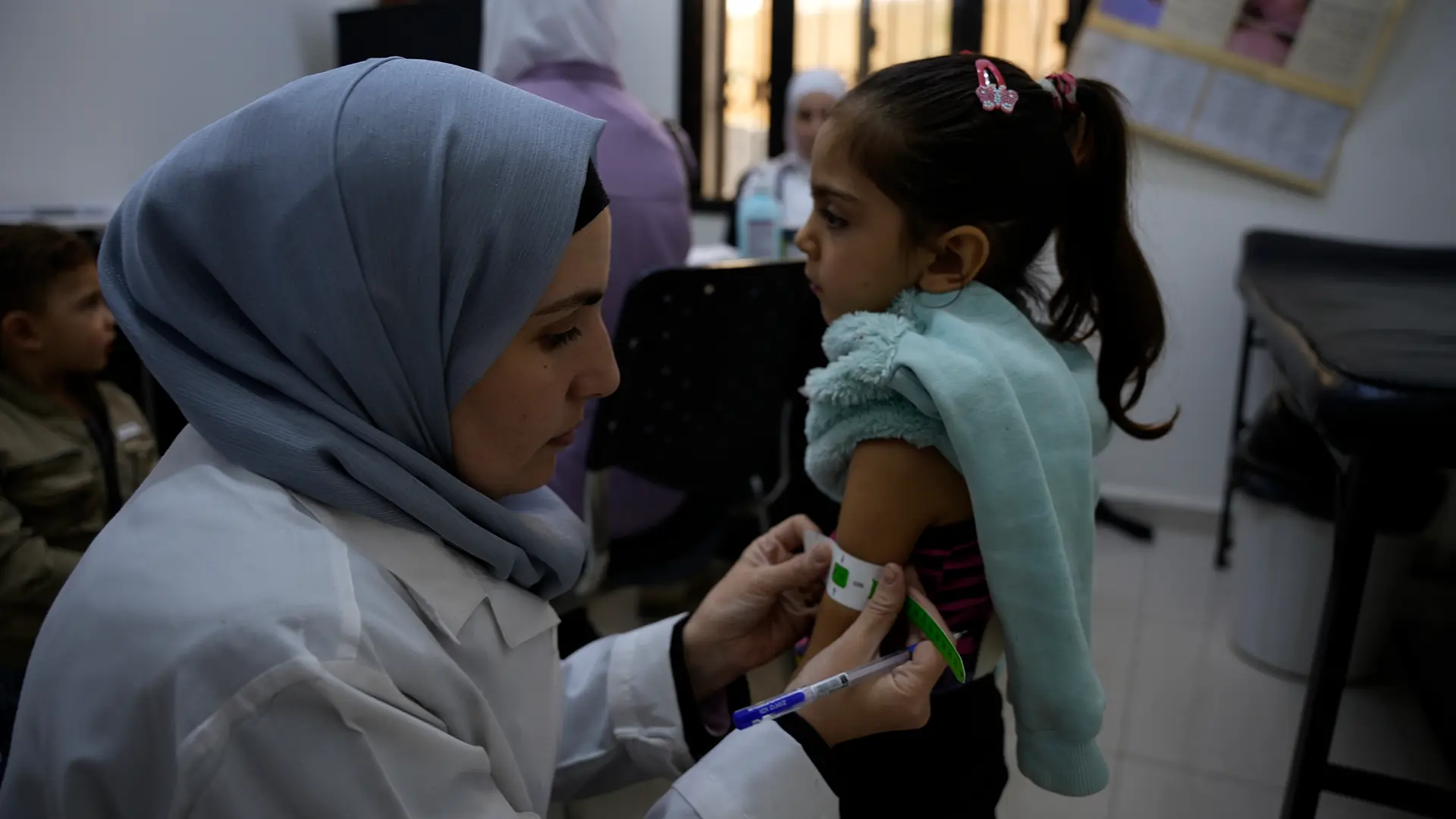 La enfermera Nawal, de la Dirección de Salud, controla la circunferencia del brazo medio superior para evaluar el estado nutricional de Hanan, de 5 años, en la clínica pediátrica del centro de atención primaria de salud de Daraya, en la zona rural de Damasco.