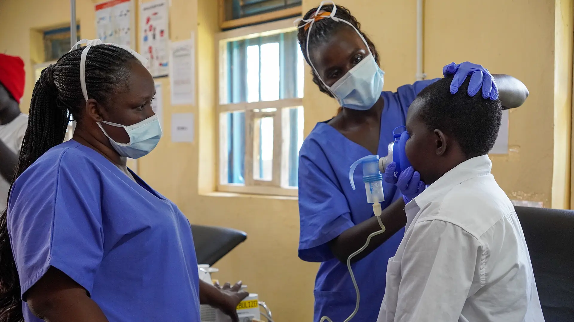 La mentora clínica Florence observa a la enfermera Agnes administrando medicamentos a un paciente a través de un nebulizador en la sala de emergencias.