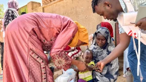 Un voluntario comunitario y un miembro del personal de MSF realizan un cribado MUAC, en Mohamed Ayoub, de 18 meses, inmediatamente después de su vacunación contra el sarampión.