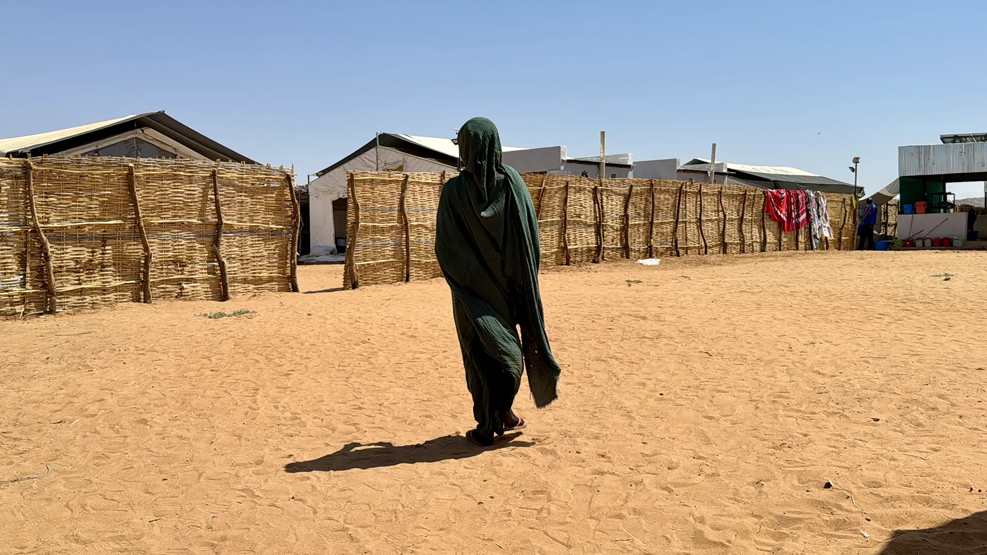 Halima* se encuentra frente a refugios improvisados ​​en Tawila. Mientras huía de El Fasher, Halima fue interceptada por hombres armados, antes de escapar con su hermana. Estado de Darfur del Norte, Sudán, febrero de 2026. *Se ha utilizado un seudónimo para proteger su identidad.
