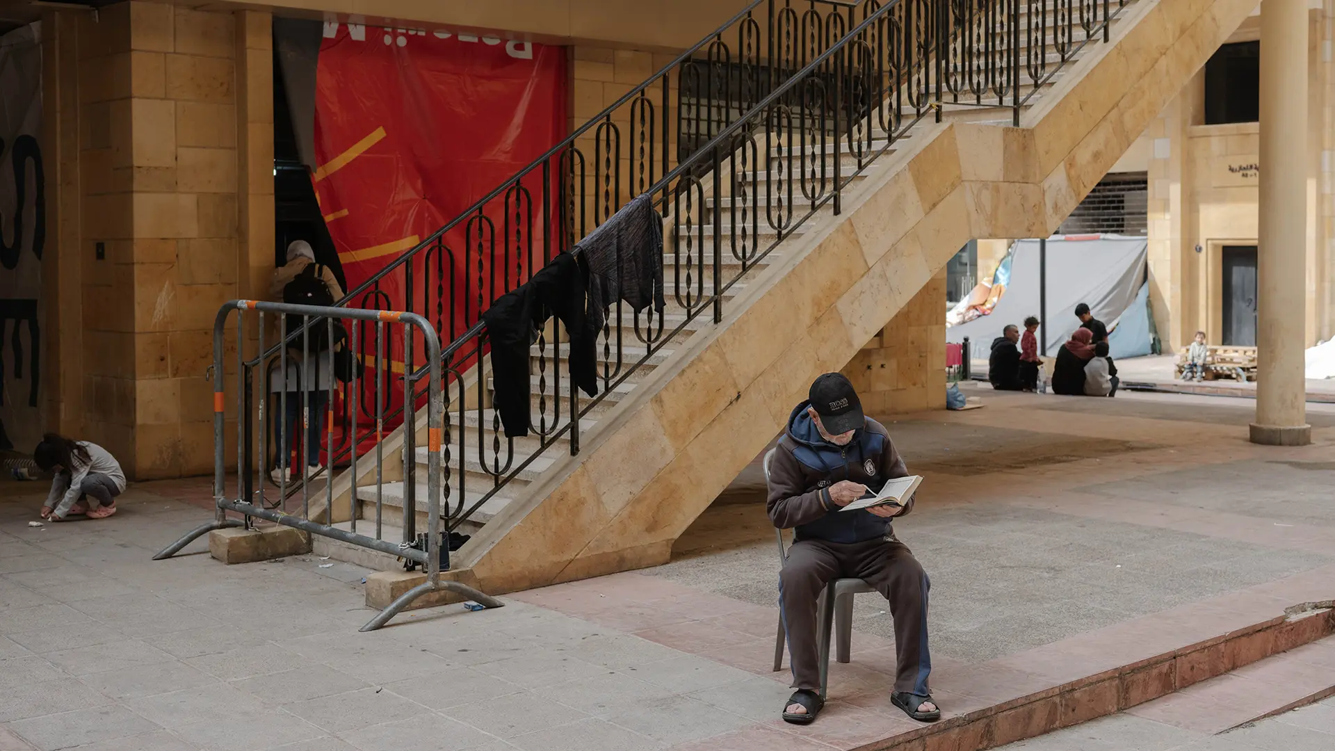 Un hombre lee un libro en el refugio Azarieh, en el centro de Beirut, donde familias desplazadas se resguardaron en un edificio abandonado. Beirut, Líbano, marzo de 2026.