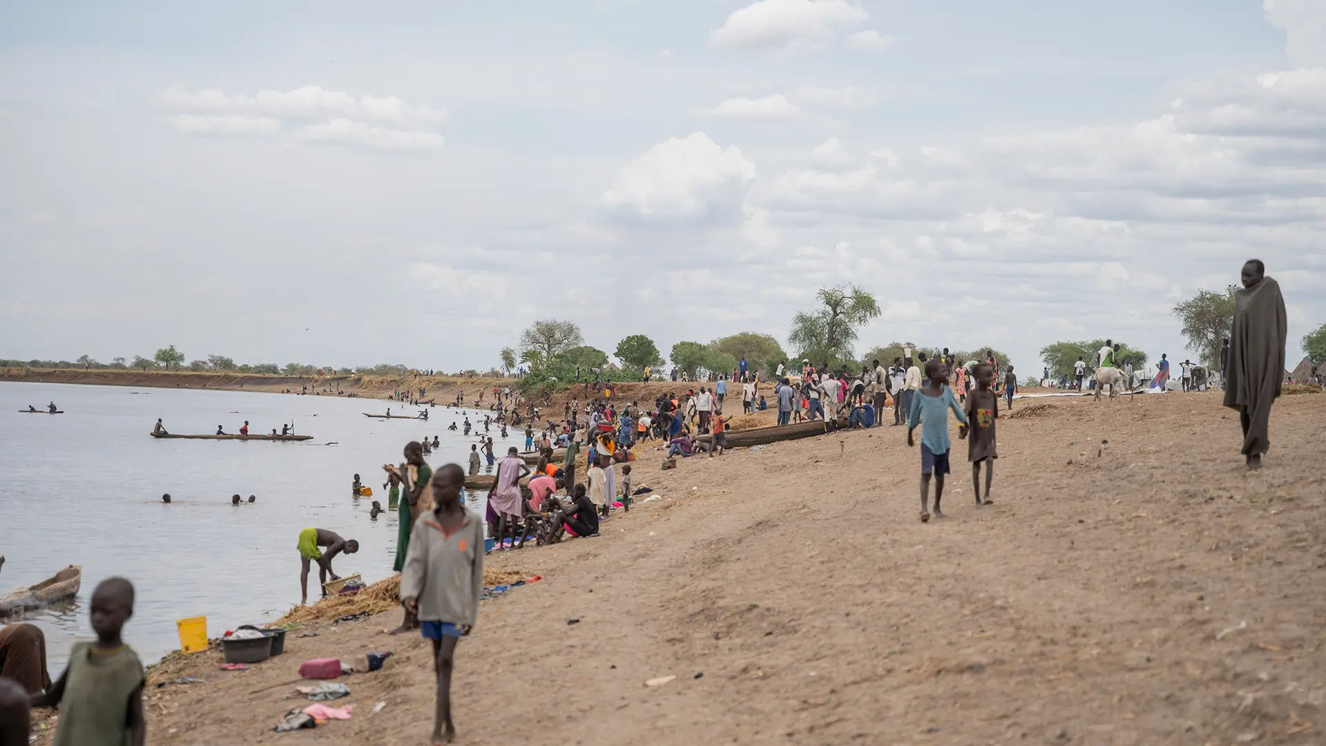 La gente realiza actividades diarias a lo largo de la orilla del río en Chuil, estado de Jonglei, Sudán del Sur, donde las familias desplazadas dependen del río para agua, lavarse y cocinar tras huir de la violencia