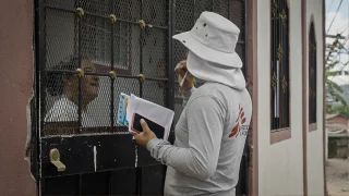 David, promotor de salud de MSF, conversa con una vecina de la comunidad para informarle sobre la liberación de mosquitos con Wolbachia que MSF planea realizar en esta zona de Tegucigalpa.