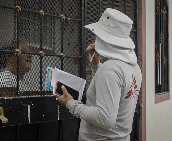 David, promotor de salud de MSF, conversa con una vecina de la comunidad para informarle sobre la liberación de mosquitos con Wolbachia que MSF planea realizar en esta zona de Tegucigalpa.