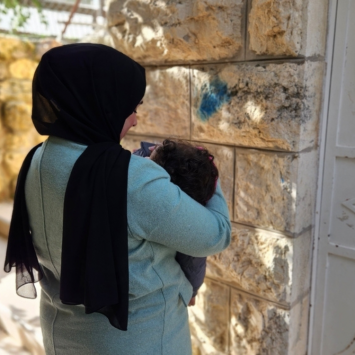Aliyah*, una mujer palestina sostiene a su hija. Vivió durante 25 años en la antigua ciudad de Hebrón, una de las zonas más restringidas de Cisjordania. Palestina, 14 de diciembre de 2023. 
© Laora Vigourt/MSF