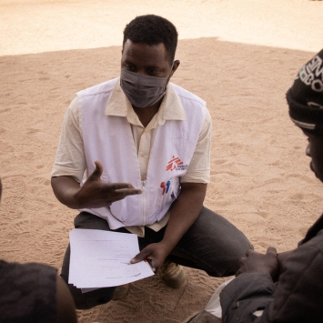 Issuf, mediador cultural de MSF, hablando con dos personas migrantes. © Yarin Trotta del Vecchio