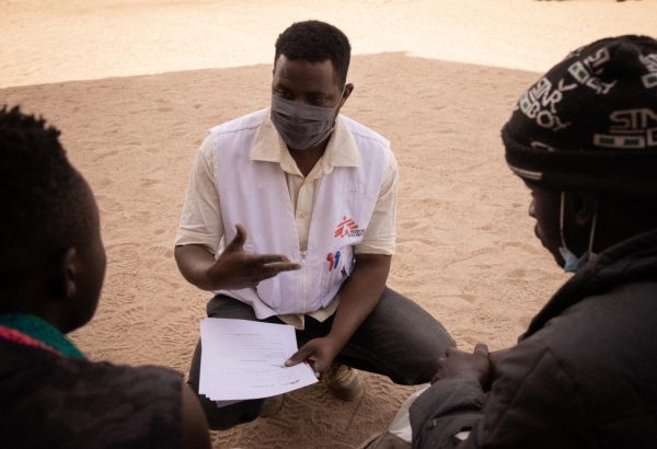 Issuf, mediador cultural de MSF, hablando con dos personas migrantes. © Yarin Trotta del Vecchio
