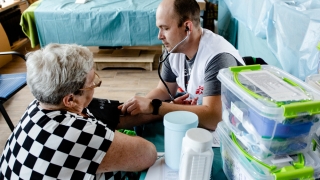 Igor Bodnia, médico ucraniano de MSF, escuchando a su paciente durante una de las clínicas móviles de MSF. La clínica se instaló en un restaurante qu se convirtió en un centro de ayuda humanitaria en Járkiv. © Pavel Dorogoy