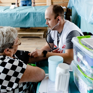 Igor Bodnia, médico ucraniano de MSF, escuchando a su paciente durante una de las clínicas móviles de MSF. La clínica se instaló en un restaurante qu se convirtió en un centro de ayuda humanitaria en Járkiv. © Pavel Dorogoy