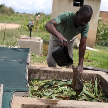 Un hombre cuidando el compostador en Zimbabue