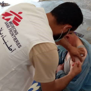 Un integrante de Médicos Sin Fronteras vacunando a una persona contra la COVID-19 en Siria
