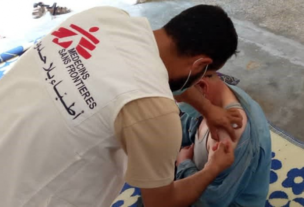 Un integrante de Médicos Sin Fronteras vacunando a una persona contra la COVID-19 en Siria