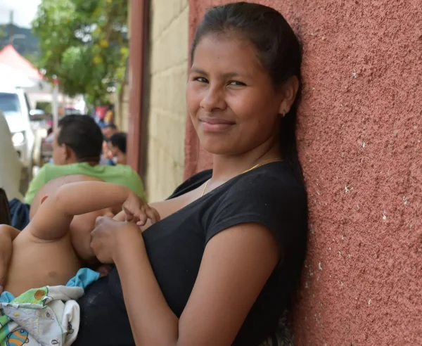 La hija mayor de la familia Brito amamantando a su hijo mientras espera que su familia reciba consulta médica.