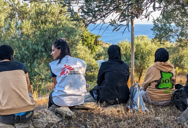 Un miembro del equipo de MSF se sienta con un grupo de recién llegados a Lesbos, quienes descansan tras recibir asistencia de nuestros equipos y agua y comida.