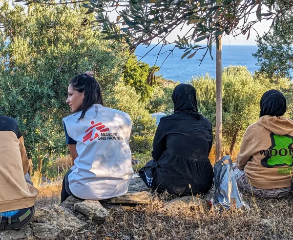 Un miembro del equipo de MSF se sienta con un grupo de recién llegados a Lesbos, quienes descansan tras recibir asistencia de nuestros equipos y agua y comida.