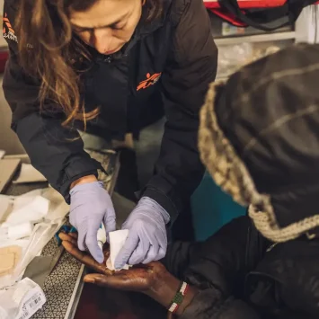 Personal de Médicos Sin Fronteras hace curación en la mano de un migrante menor no acompañado