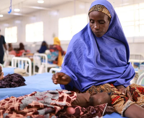 Asma'u se sienta junto a su hija, Shamsiya, quien ha sido ingresada en el centro de alimentación terapéutica para pacientes hospitalizados Kofar Suari por desnutrición, en el estado de Katsina, Nigeria, en octubre de 2024.