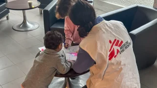 Dos niños iraníes con su madre en Calais. MSF les dio cobijo. Aquí juegan con una trabajadora de MSF. © Mohammad Ghannam / MSF