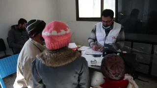Mohammed Gobasi, trabajador médico de MSF, proporciona una receta a un padre con sus dos hijos en las clínicas móviles de MSF en Guta Oriental. © Omar Haj Kadour
