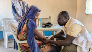 Una médica de MSF examina a Sameera Abkir en la clínica móvil Romalia, en Darfur Occidental. Desarrolló una infección en el brazo debido a una inyección mal administrada tras un parto en casa. Sudán, enero de 2025.