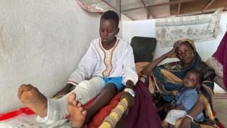 Adil se incorpora en la cama del pabellón pediátrico del hospital de Tawila, mientras su madre, Nawal, y su hermano, Musa, se sientan a su lado.