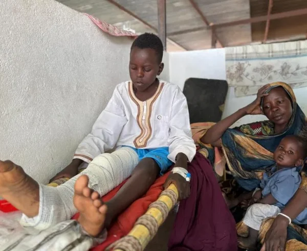 Adil se incorpora en la cama del pabellón pediátrico del hospital de Tawila, mientras su madre, Nawal, y su hermano, Musa, se sientan a su lado.