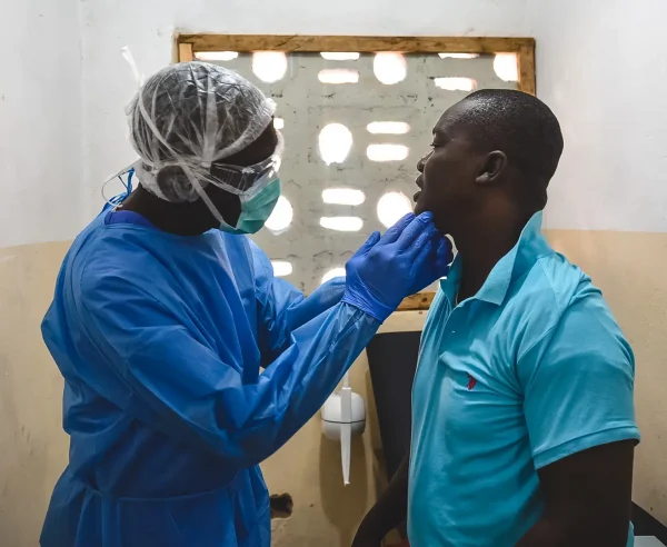 George Kamara, oficial de salud comunitaria de MSF, examina a un paciente dentro del centro de tratamiento mpox en la ciudad de Calaba, Freetown, Sierra Leona, junio de 2025.