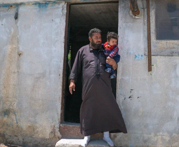 Walid y su hijo menor fuera de su refugio en el campamento de Al-Kuwaiti, Idlib, al noroeste de Siria.