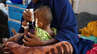 Una mujer sostiene a su hijo, quien sufre desnutrición, y le alimenta con una jeringa en el Hospital Bay Regional que apoyamos en Baidoa, en Somalia.