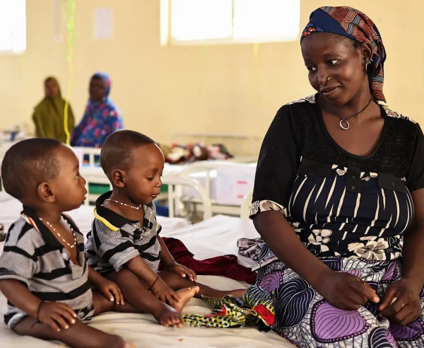 Binta Abdulraziqu junto a sus hijos gemelos, quienes fueron ingresados ​​por desnutrición aguda grave en el centro de nutrición terapéutica para pacientes hospitalizados de Maiyama. Estado de Kebbi, Nigeria, agosto de 2025.